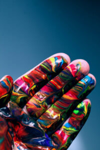 hand covered in rainbow paint against a blue sky