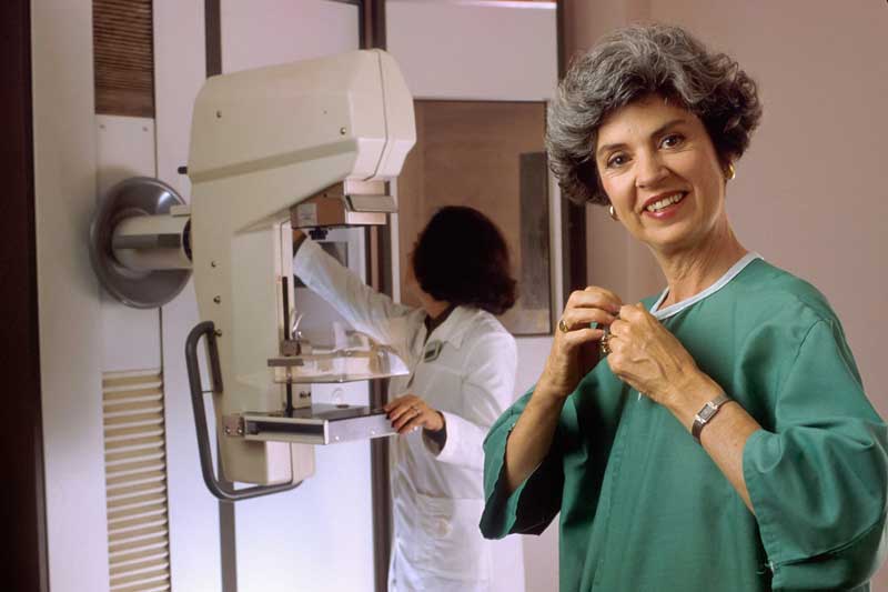 patient standing next to breast cancer imaging equipment