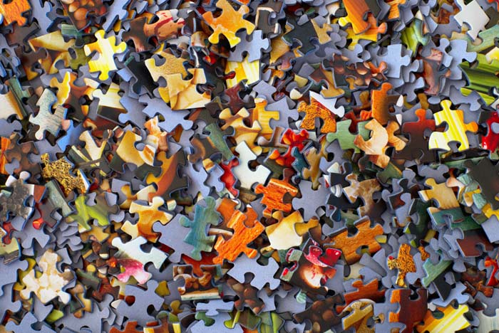 A close up image of mixed-up puzzle pieces.
